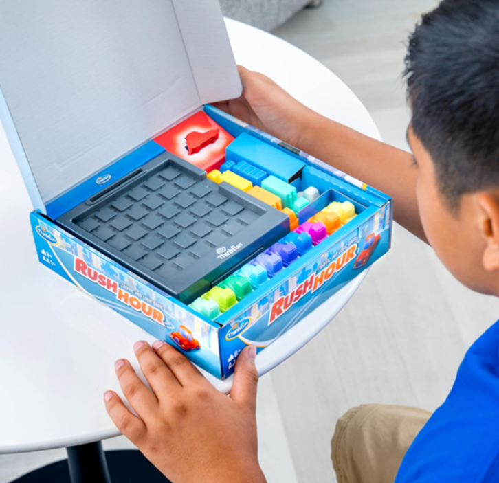 Child playing with a Rush Hour game set on a table