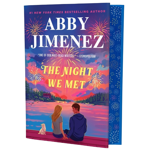Book cover of 'The Night We Met' by Abby Jimenez with a couple and dog by a lake at sunset.